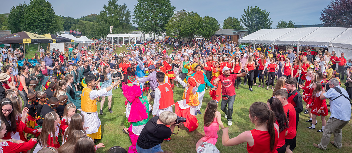 A crowd of people watching dancers perform outdoors at Llangollen International Musical Eisteddfod