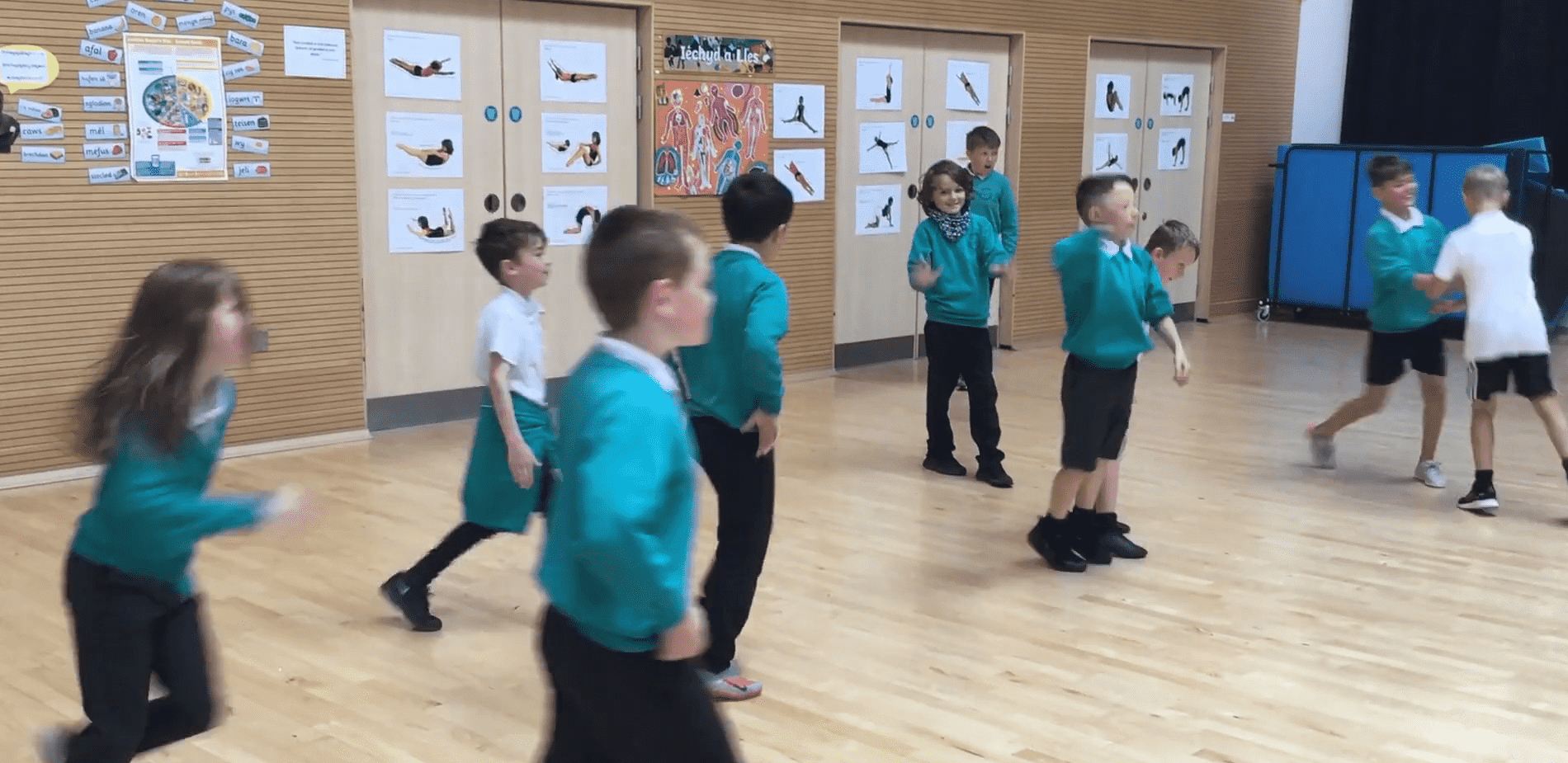 A group of school children running in a sports hall. 