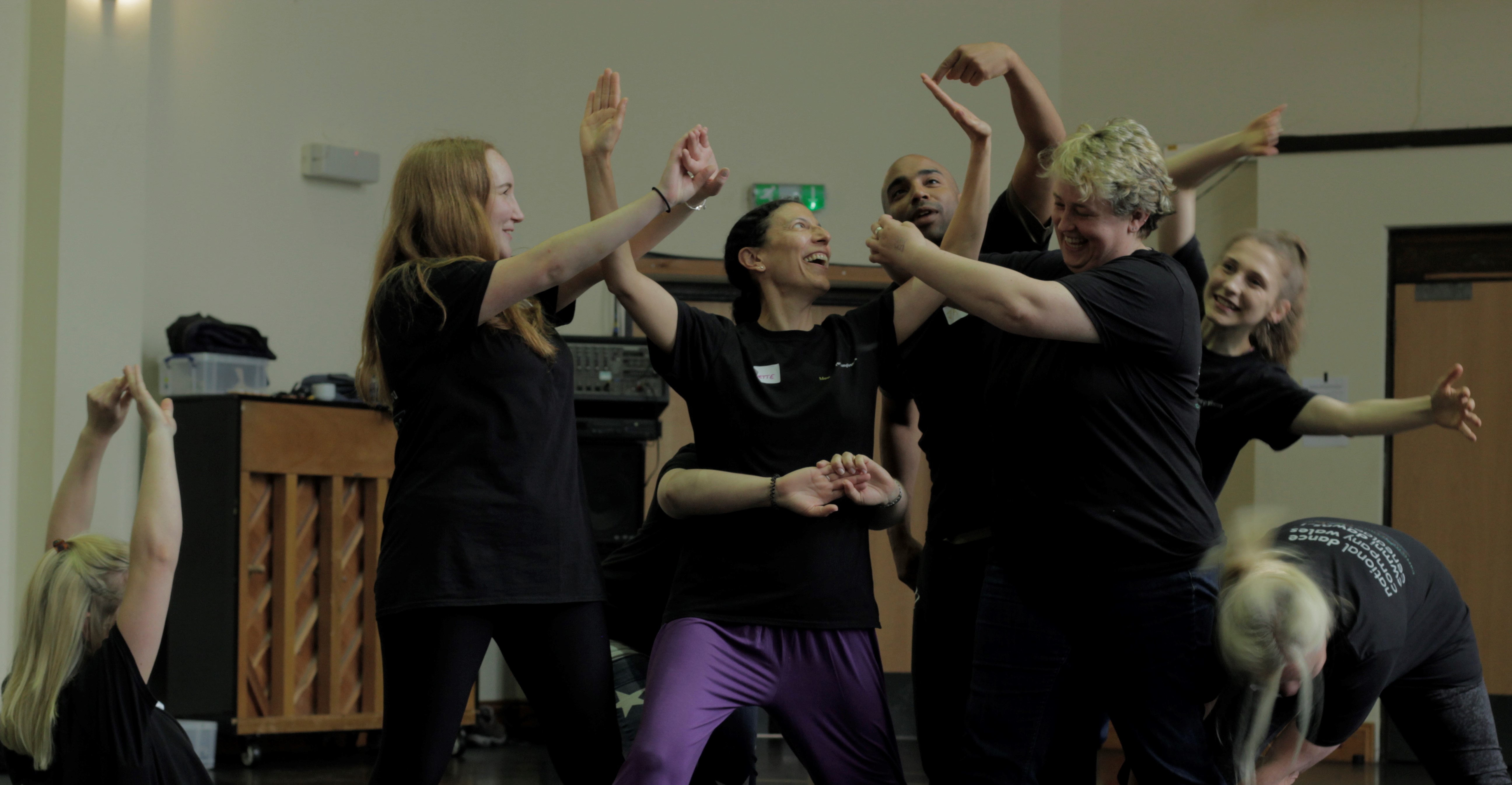 Seven staff from Cartrefi Cymru Co-operative engaging in a dance-based exercise with National Dance Company Wales