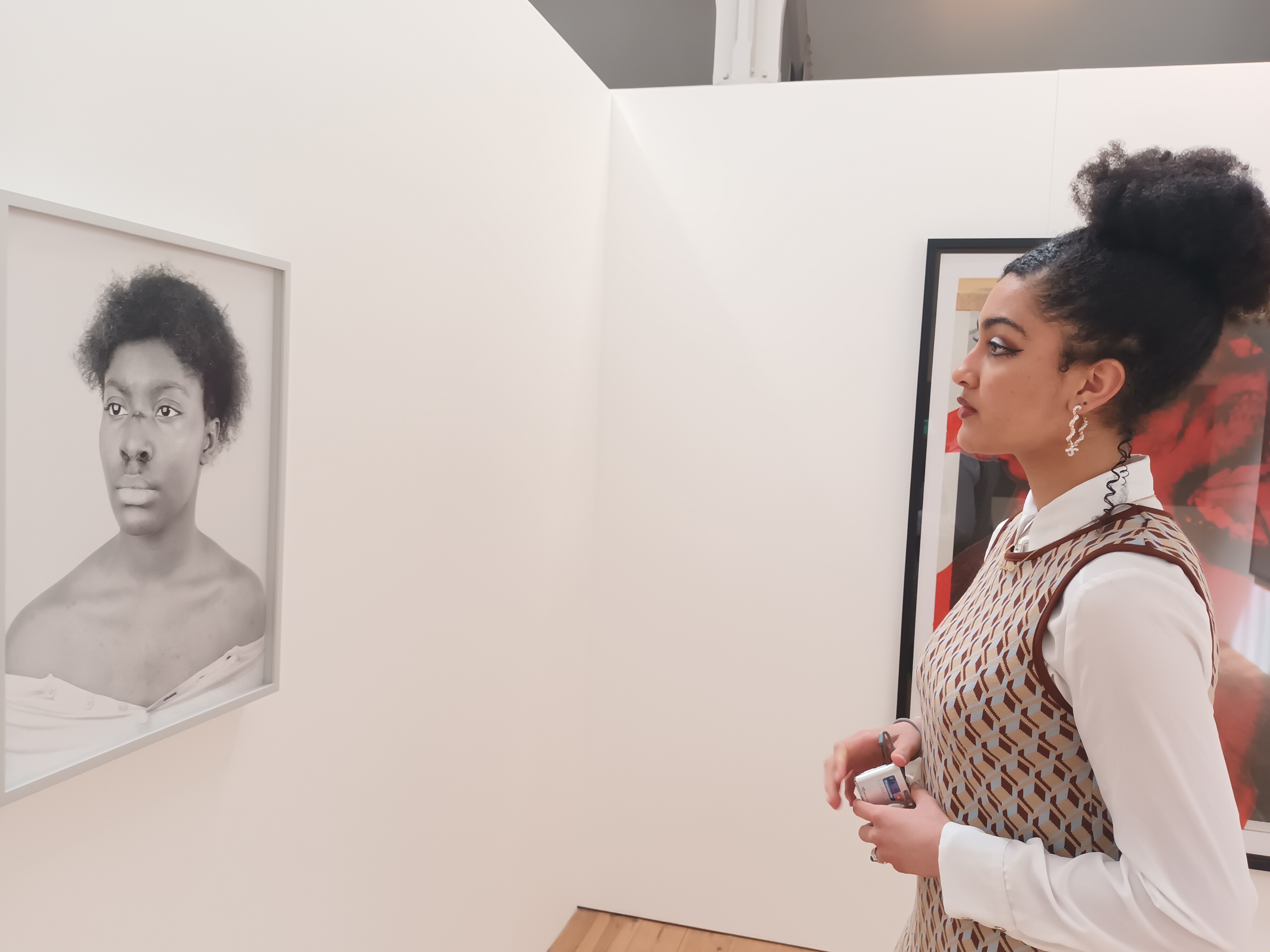 A person staring at a portrait hung on an art gallery wall