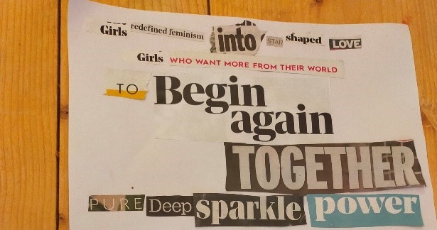 A piece of white paper lying on a wooden background. Glued to the paper are random newspaper cut-outs depicting the following sentences – ‘Girls redefined feminism into star shaped love’; Girls who want more from their world’; ‘To begin again together’. 