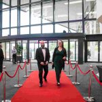 Two people walking down a red carpet and smiling