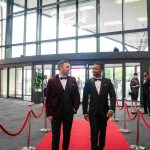 Two people walking down a red carpet and smiling