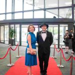 Two people standing on a red carpet and smiling