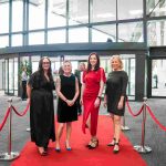 Four people standing on a red carpet and smiling