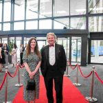 Two people standing on a red carpet and smiling