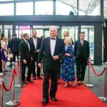 One person walking down a red carpet with five other people behind