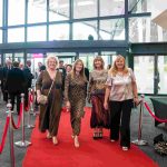 Four people walking down a red carpet and smiling