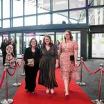 Three people walking down a red carpet and smiling