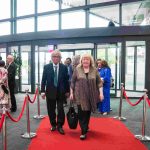 Two people walking down a red carpet and smiling