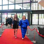 Two people walking down a red carpet and smiling