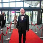 One person standing on a red carpet and smiling