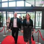 Two people walking down a red carpet and smiling