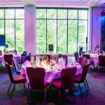 Laid tables in front of a large window looking out at green trees