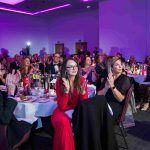 People sat at a dinner table watching a live performance