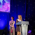 Actor Nia Roberts standing behind a lectern on a presentation stage