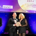 Two people from Port of Milford Haven standing on stage, holding an award and smiling at the camera