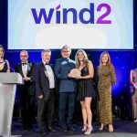 People from Wind2 holding an award, smiling at the camera with TV presenter and designer Anna Ryder Richardson