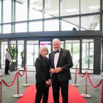 Two people standing on a red carpet and smiling