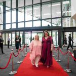 Two people standing on a red carpet and smiling